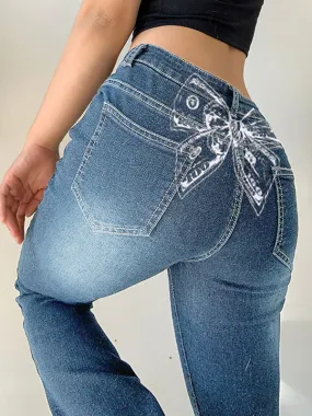 Jeans acampanados de cintura baja lavados con estampado de lazo